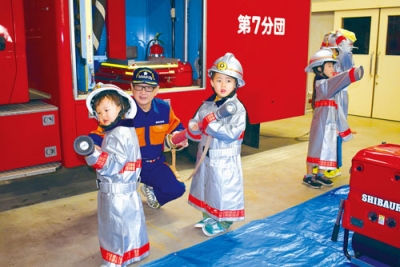 写真：防火服を着て消防士の気分を味わう子どもたち＝室蘭市消防本部