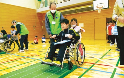 写真：車いす体験を行う児童たち