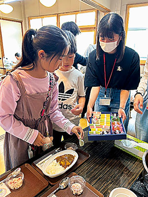 写真：手作りカレーと富留屋の菓子を受け取る来場者（提供写真）