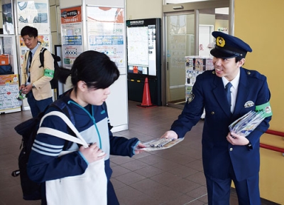 写真：「地域安全運動」初日、学生に啓発物を手渡す室蘭署員