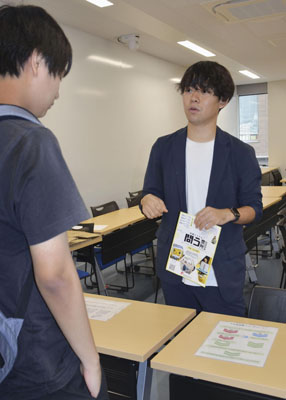 写真：学生に不在者投票のやり方を説明する、学生団体代表の藤田星流さん（右）＝１６日、東京都文京区の中央大茗荷谷キャンパス