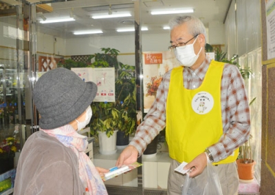 写真：買い物客にチラシを配る松橋理事長