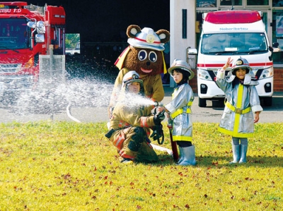 写真：防火衣を着て放水体験をする年長児