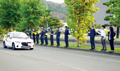 写真：小旗を振り車両パレードを見送る「人と旗の波運動」の参加者たち