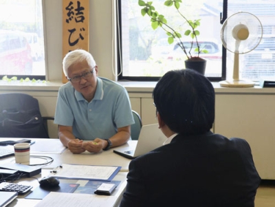 写真：会員登録した男性（手前）と面談する「お結び課」の森一也課長＝９月、佐賀県武雄市役所山内支所