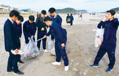 写真：イタンキ浜のごみを拾い集める生徒たち