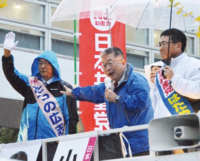 写真：雨が降る中、立野候補（左）の支援を呼びかける小池晃事務局長（中央）と比例道ブロックの畠山候補＝午後４時ごろ、苫小牧市木場町