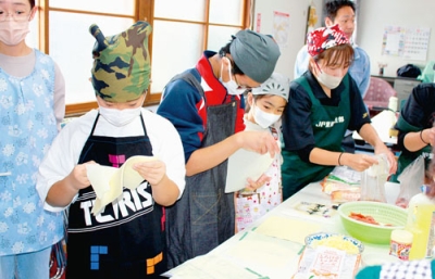 写真：地場産サケを調理する子どもたち＝本輪西町会館（提供写真）