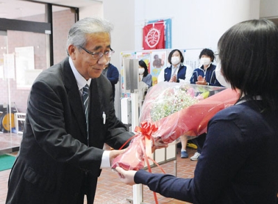 写真：初登庁で女性職員から花束を受け取る杉谷町長（左）