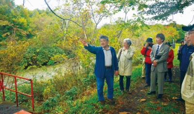 写真：登別川沿いでバードの渡河地点を考察する松本副館長（左）と参加者たち