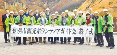 写真：紅葉鮮やかな地獄谷で記念撮影する会員たち