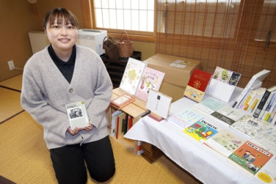 写真：「かぷりば」で販売している本を手に取る川村佳恵さん＝山形県金山町