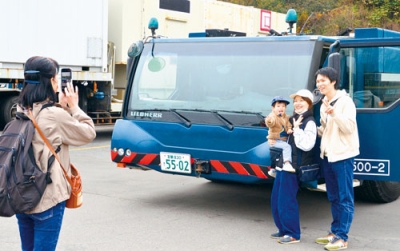 写真：建設用クレーン車の前で記念撮影をする参加者