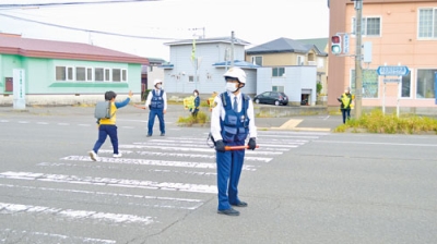 写真：横断する小学生を見守る参加者たち