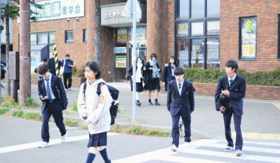 写真：コートやマフラーなどを身に着けて歩く学生たち＝５日午後、ＪＲ東室蘭駅西口前