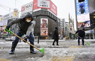 写真：札幌市の繁華街・ススキノで雪かきをする人たち＝７日午前