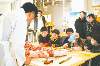 写真：熟成豚で食肉加工の実演を見学する参加者