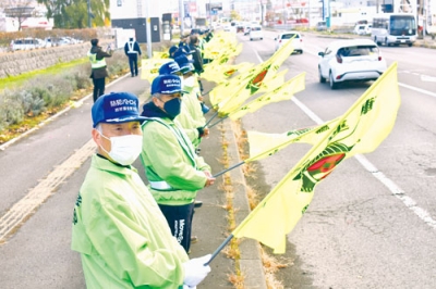 写真：国道で旗を掲げ、ドライバーに冬型事故への注意を呼びかける参加者