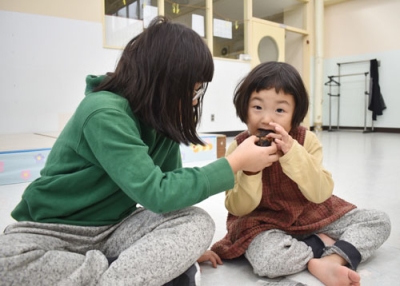 写真：熱々の焼き芋を頬張り交流を深める児童と園児