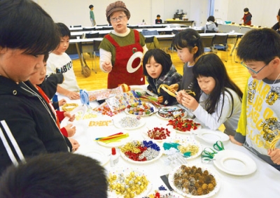 写真：山田会長からクリスマスリースの作り方を教わる子どもたち