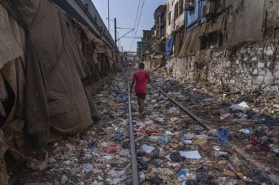 写真：プラスチックごみなどが散乱した線路を歩く男性＝４月、インド・ムンバイ（ＡＰ＝共同）