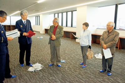 写真：消防本部の事務室を見学する三浦会長（右端）ら