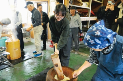 写真：きねを振り下ろし餅をつく留学生たち