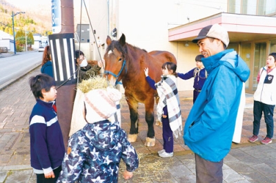 写真：農耕馬と触れ合い、鑑賞の余韻に浸る参加者（提供写真）