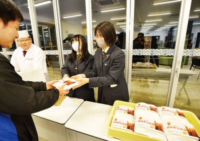 写真：鬼花火のラベルを貼った「旅するのぼめし弁当」を販売する生徒たちと渡辺会長