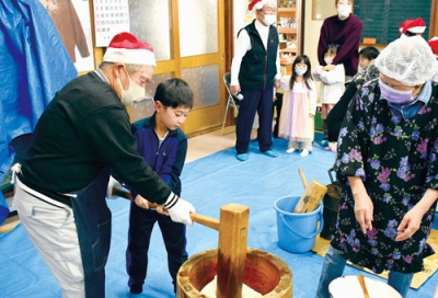 写真：町会役員と一緒に一生懸命に餅をつく子どもたち