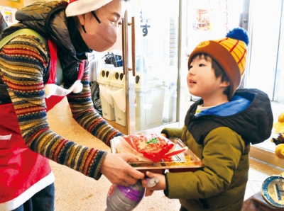 写真：弁当とケーキを子どもに渡すなかよし食堂のメンバー