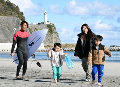 写真：福島県いわき市の平豊間地区に移住し、家族とともに海岸を歩く石沢大河さん（左端）