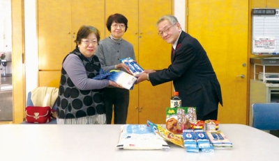 写真：國枝会長（右）に食品を手渡す消費者協会のメンバー（提供写真）