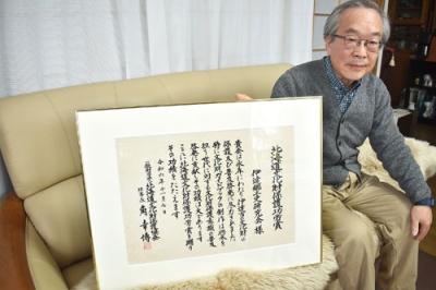 写真：「これからも活動を続けたい」。賞状を手に展望を語る浪越会長