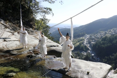 写真：「那智の滝」の上に架かるしめ縄を張り替える熊野那智大社の神職＝２７日午前、和歌山県那智勝浦町