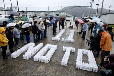 写真：能登半島地震の発生時刻に合わせて黙とうする人たち＝１日午後４時１０分、石川県輪島市町野町