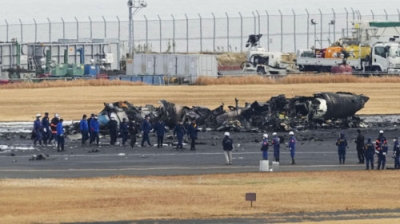 写真：日航機と衝突し、焼け焦げた海上保安庁の航空機の周辺に集まる警視庁の捜査員や東京消防庁の隊員ら＝２０２４年１月３日、羽田空港