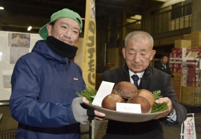 写真：過去最高額で競り落とされた「のとてまり」を持つ仲買人の浅市佳男さん。右は「奥能登原木しいたけ活性化協議会」の樋下義勝会長＝９日午前、金沢市