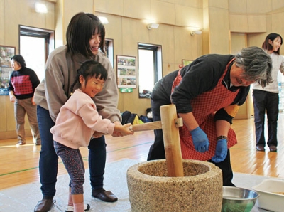 写真：笑顔で餅つきに挑戦する親子