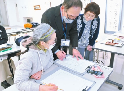 写真：佐藤館長（真ん中）から透視図法や陰影の付け方などを学ぶ参加者たち