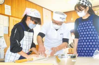 写真：室蘭手打ちそば愛好会の会員（中央）に指導を受けながらそば打ちに挑戦する参加者