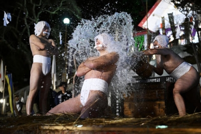 写真：神事「寒中みそぎ」で冷水を浴びて身を清める下帯姿の「行修者」＝１３日夜、木古内町の佐女川神社