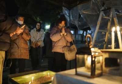 写真：阪神大震災から３０年となり、神戸市長田区の大国公園で発生時刻に合わせ黙とうする人たち＝１７日午前５時４６分