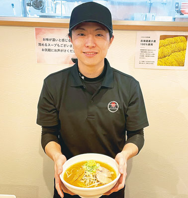 写真：「味噌らぁめん」を手に店舗をＰＲする佐野代表