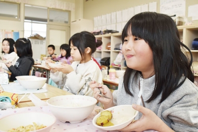 写真：おいしそうに大学イモを食べる東小２年生の児童たち