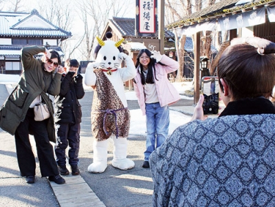 写真：ニャンまげと一緒に記念撮影する観光客