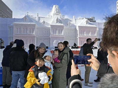 写真：「さっぽろ雪まつり」を楽しむ親子連れ。後方は道庁旧本庁舎をかたどった大雪像＝４日午前、札幌市の大通公園