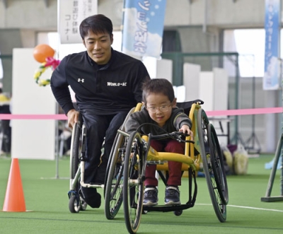 写真：２０２４年１２月に開かれた競技用車いすの体験会で、子どもと伴走する生馬知季さん＝岡山市