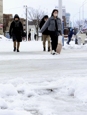 写真：雪が積もったＪＲ新潟駅前を歩く人たち＝６日午前、新潟市