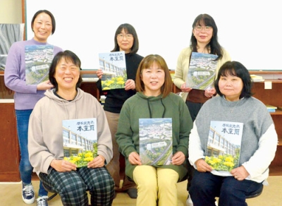 写真：閉校記念誌を手にする編集ボランティアの６人 